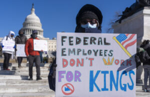 Efectivo máximo para los amigos de Trump, y el máximo dolor para todos los demás FILE - A federal employee, who asked not to use their name for fears over losing their job, protests with a sign saying "Federal Employees Don't Work for Kings" during the "No Kings Day" protest on Presidents Day in Washington, in support of federal workers and against recent actions by President Donald Trump and Elon Musk, Feb. 17, 2025, by the Capitol in Washington. (AP Photo/Jacquelyn Martin, File)